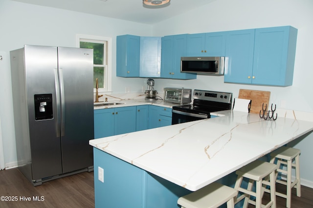 kitchen with sink, stainless steel appliances, blue cabinetry, and kitchen peninsula