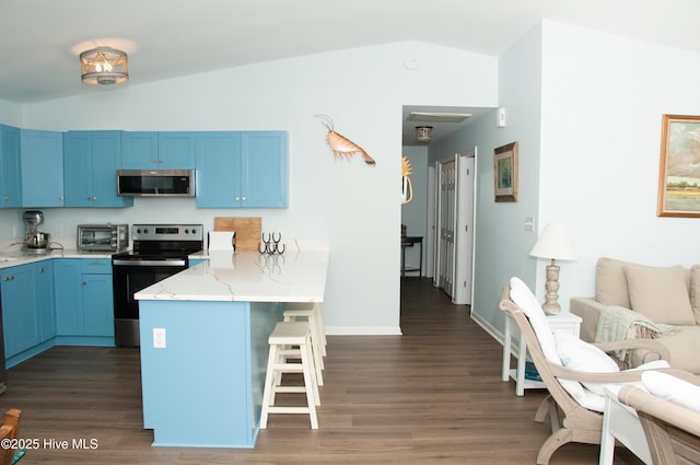 kitchen featuring stainless steel appliances, vaulted ceiling, blue cabinetry, and a breakfast bar area