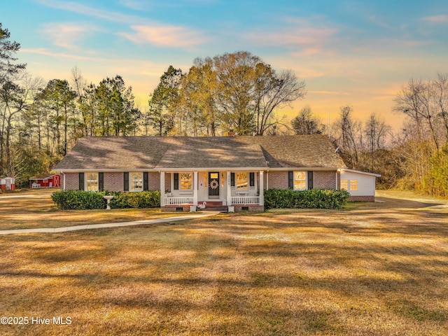 ranch-style home featuring covered porch and a lawn