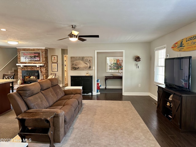 living room with a brick fireplace, ceiling fan, and dark hardwood / wood-style floors