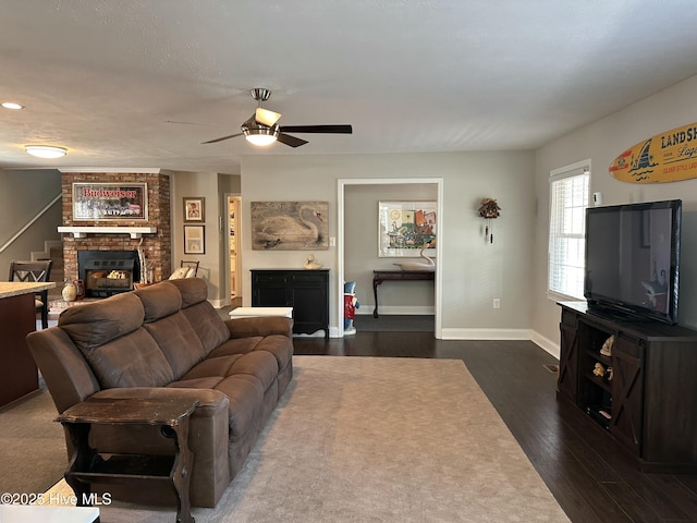 living room featuring ceiling fan, dark wood-type flooring, and a brick fireplace