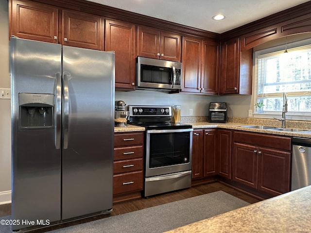 kitchen with appliances with stainless steel finishes, dark hardwood / wood-style flooring, and sink