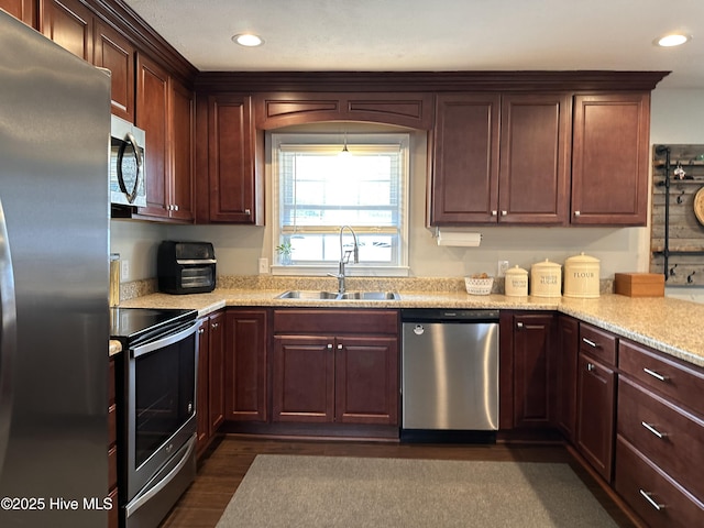 kitchen with sink, light stone countertops, dark hardwood / wood-style floors, and appliances with stainless steel finishes