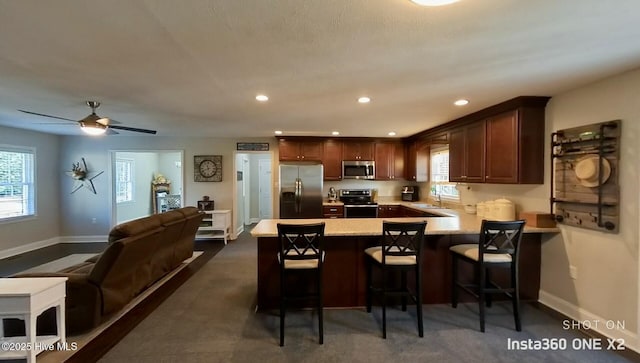 kitchen featuring plenty of natural light, kitchen peninsula, appliances with stainless steel finishes, and a kitchen bar