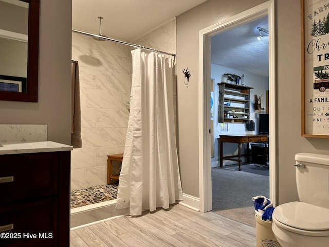 bathroom featuring toilet, a textured ceiling, walk in shower, wood-type flooring, and vanity