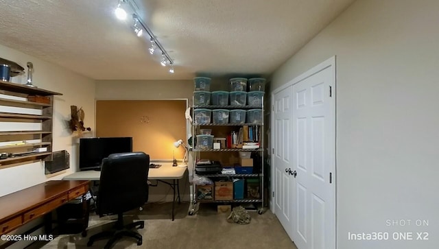 carpeted office featuring rail lighting and a textured ceiling