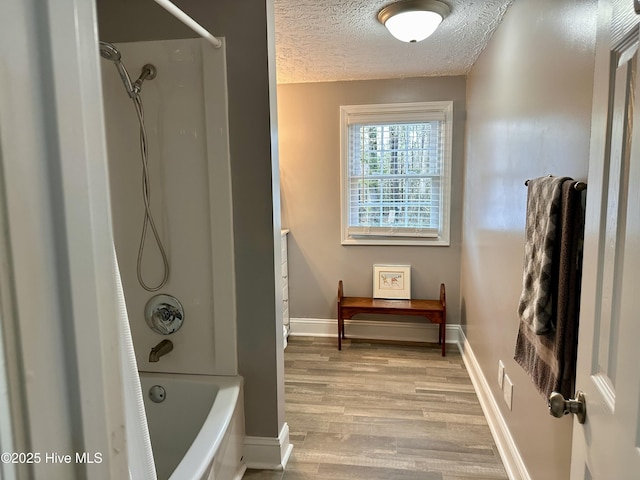 bathroom featuring a textured ceiling, bathing tub / shower combination, and hardwood / wood-style floors