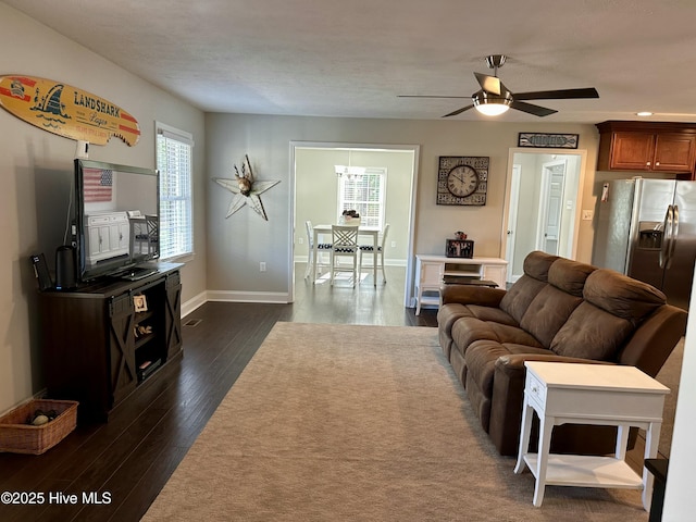 living room featuring ceiling fan and dark hardwood / wood-style floors