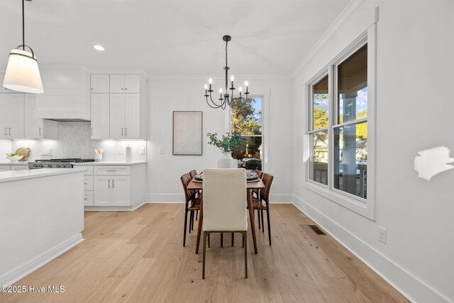 dining space featuring a chandelier, light hardwood / wood-style floors, crown molding, and a healthy amount of sunlight