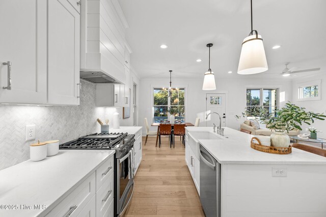 kitchen with appliances with stainless steel finishes, hanging light fixtures, decorative backsplash, white cabinets, and sink