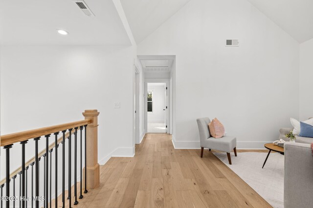 hallway with light hardwood / wood-style floors and lofted ceiling