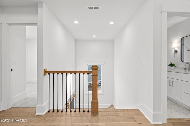 hallway with lofted ceiling and light hardwood / wood-style floors