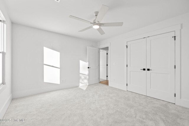 unfurnished bedroom with ceiling fan, light colored carpet, and a closet