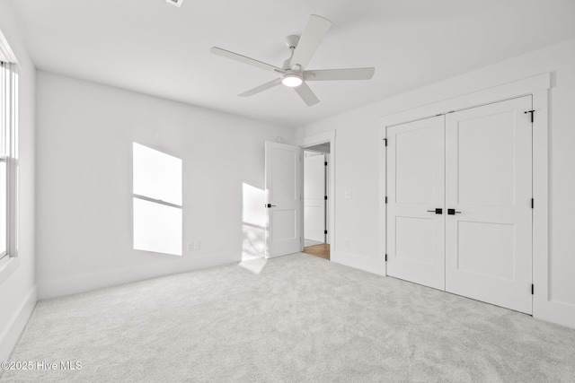 unfurnished bedroom featuring light colored carpet, ceiling fan, and a closet