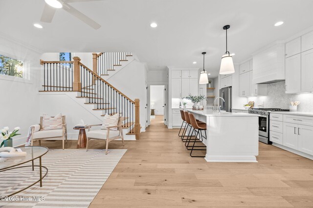 living room featuring ceiling fan, ornamental molding, and light hardwood / wood-style floors