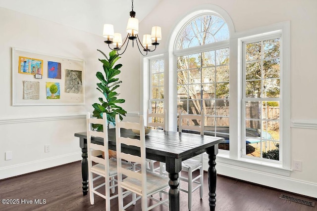 dining space featuring vaulted ceiling, dark hardwood / wood-style floors, and an inviting chandelier