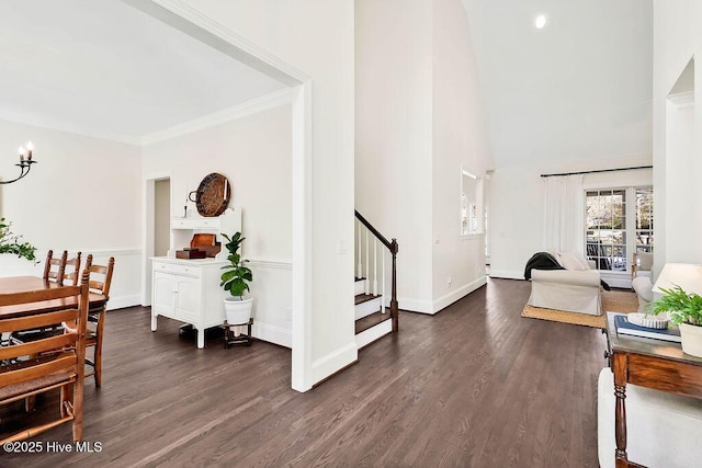 interior space featuring dark wood-type flooring, ornamental molding, a towering ceiling, and a chandelier