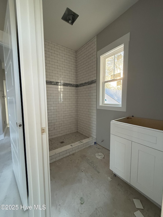 bathroom with concrete floors and a tile shower