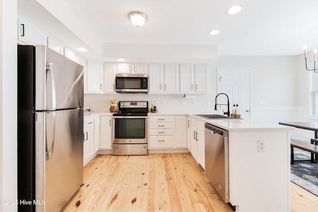 kitchen with appliances with stainless steel finishes, light hardwood / wood-style flooring, white cabinets, and sink