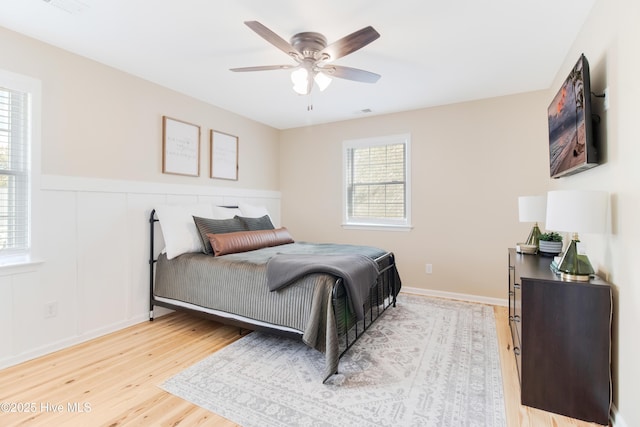 bedroom featuring light wood-type flooring, ceiling fan, and multiple windows