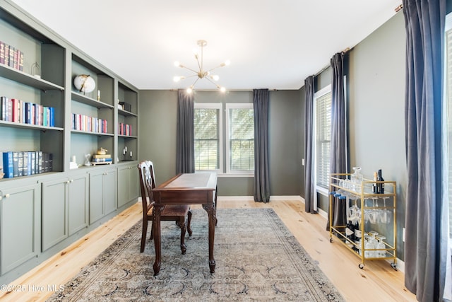 office area with built in shelves, light hardwood / wood-style flooring, and a notable chandelier