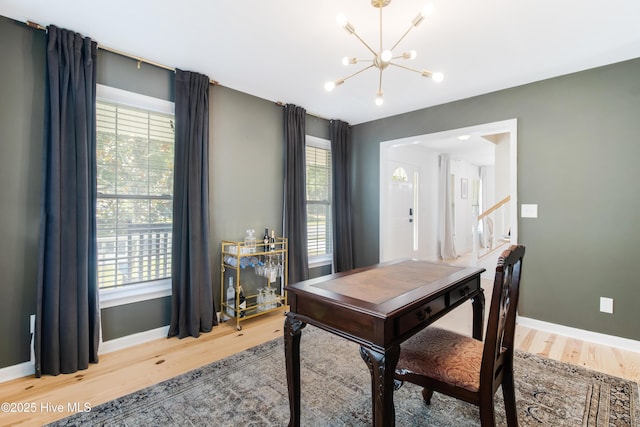 dining space with plenty of natural light, hardwood / wood-style floors, and an inviting chandelier