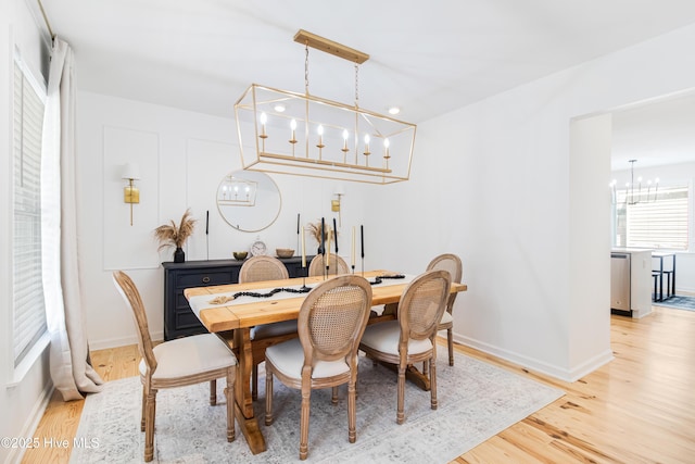 dining area with light hardwood / wood-style flooring and a notable chandelier