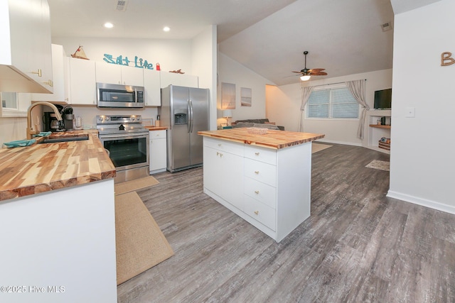 kitchen featuring white cabinetry, vaulted ceiling, ceiling fan, wood counters, and appliances with stainless steel finishes