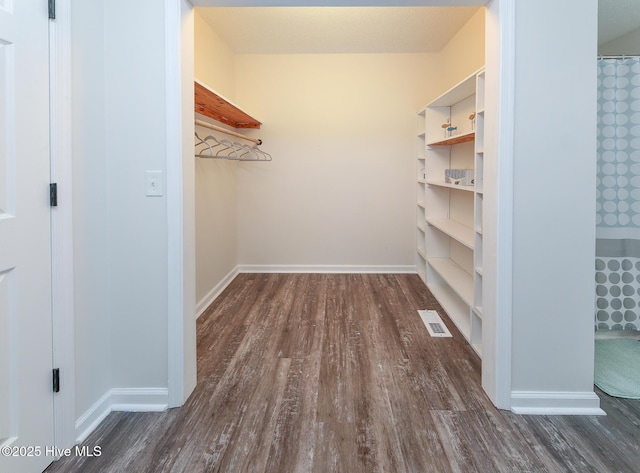 walk in closet with dark hardwood / wood-style flooring