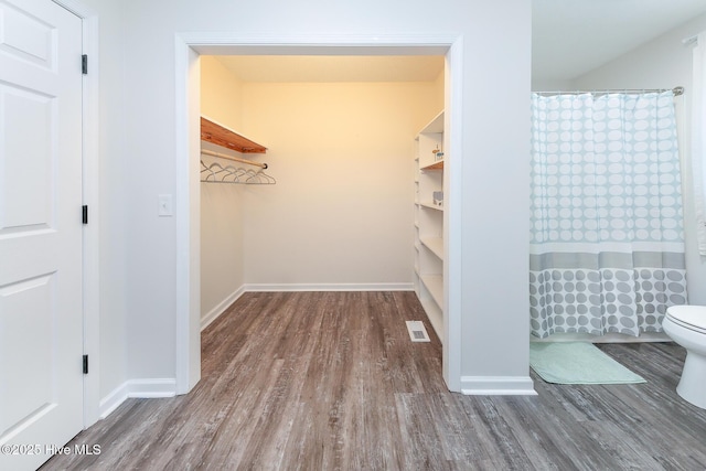 bathroom with hardwood / wood-style floors, curtained shower, and toilet