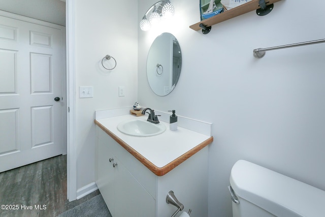 bathroom featuring toilet, vanity, and hardwood / wood-style floors