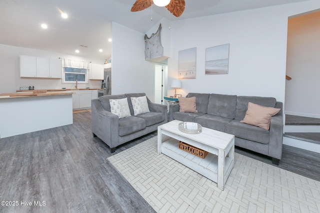 living room with ceiling fan, vaulted ceiling, and light hardwood / wood-style flooring