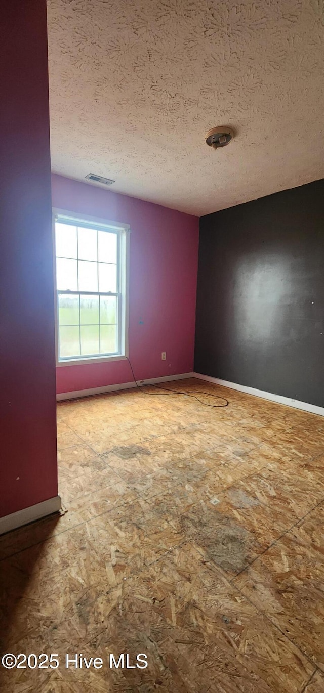 unfurnished room with a textured ceiling