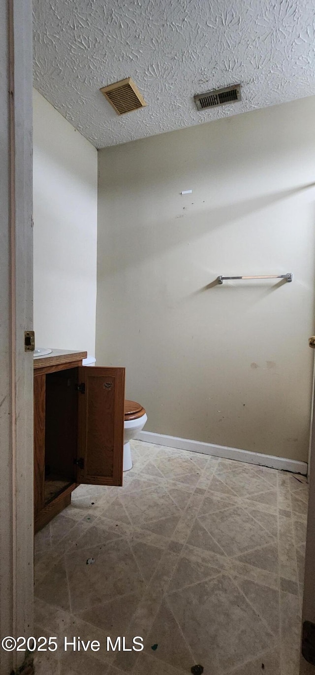 bathroom with a textured ceiling, vanity, and toilet