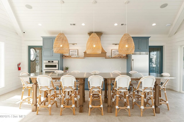 kitchen with oven, built in fridge, lofted ceiling, hanging light fixtures, and a breakfast bar