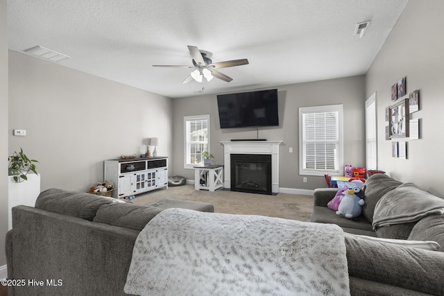 living room with ceiling fan, light colored carpet, and a textured ceiling