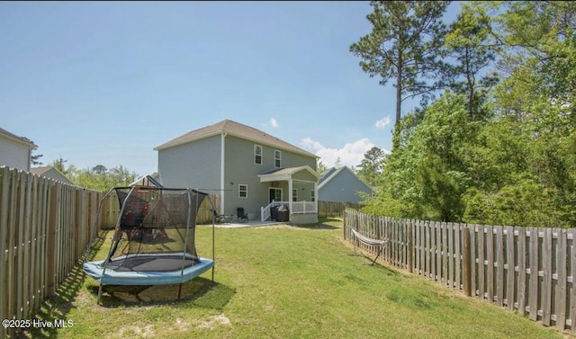 rear view of house with a yard and a trampoline