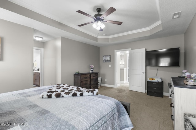 bedroom featuring ensuite bathroom, a tray ceiling, ornamental molding, ceiling fan, and light carpet