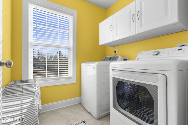 washroom with independent washer and dryer, cabinets, and light tile patterned floors