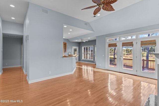 unfurnished living room featuring french doors, sink, high vaulted ceiling, ceiling fan, and light hardwood / wood-style flooring