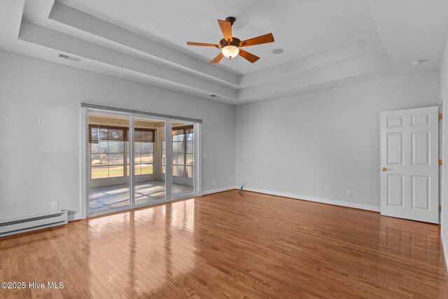 unfurnished room with ceiling fan, a baseboard radiator, wood-type flooring, and a tray ceiling