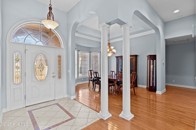 foyer featuring an inviting chandelier, light tile patterned floors, a towering ceiling, and decorative columns