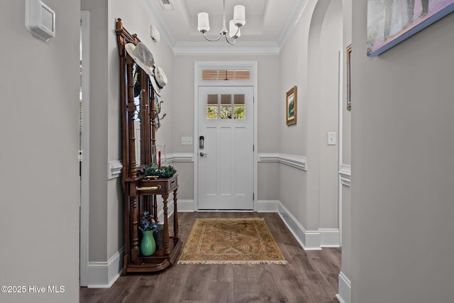 doorway to outside with dark wood-type flooring, crown molding, and an inviting chandelier