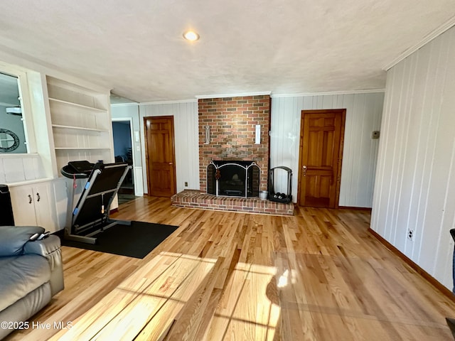 interior space featuring a brick fireplace, crown molding, light hardwood / wood-style flooring, and built in features