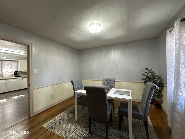 dining area featuring wood-type flooring, sink, and a textured ceiling