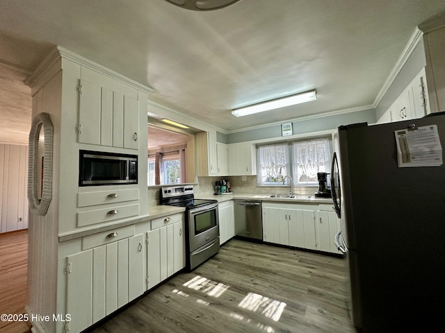 kitchen with sink, light wood-type flooring, white cabinets, and appliances with stainless steel finishes