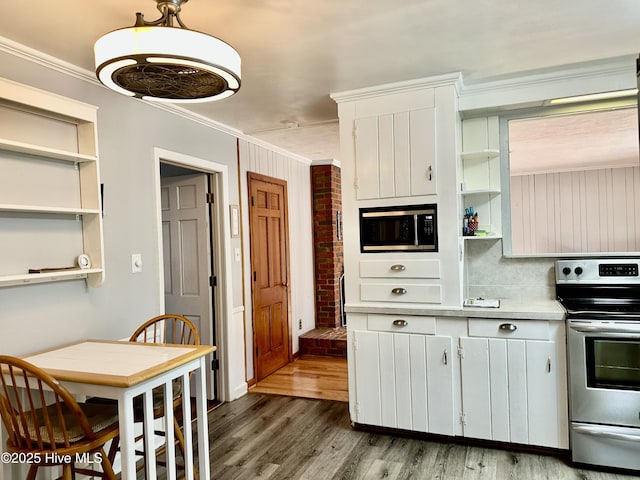 kitchen with white cabinetry, stainless steel range with electric stovetop, ornamental molding, and hanging light fixtures