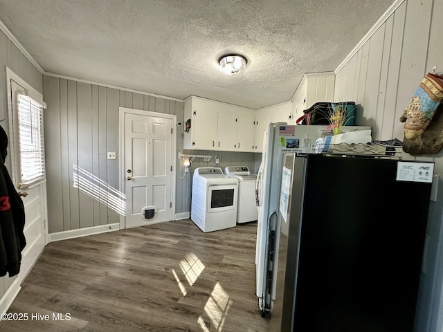 washroom featuring cabinets, a textured ceiling, ornamental molding, dark hardwood / wood-style floors, and washing machine and dryer