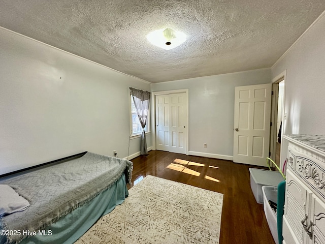 bedroom with crown molding, a textured ceiling, dark hardwood / wood-style flooring, and a closet