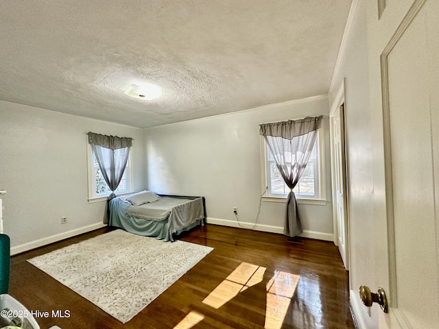 bedroom featuring multiple windows, dark wood-type flooring, and a textured ceiling